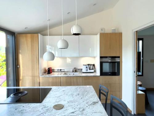 a kitchen with a counter and a table with chairs at Gîte de charme 5 étoiles pour couple avec sauna et jacuzzi extérieurs privatifs in Peaugres