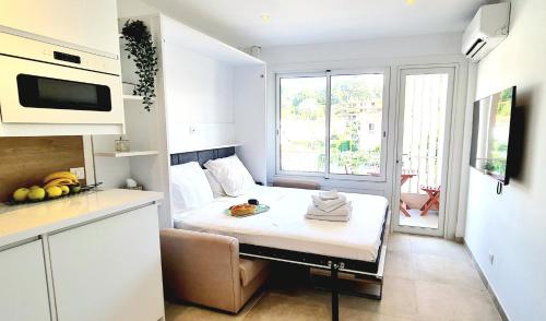 カンヌにあるStudio Cannesのベッドと窓が備わる小さな白い客室です。