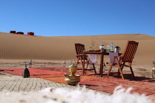 Mhamid camp activités في Mhamid: طاولة وكراسي في صحراء بها حنفية حريق