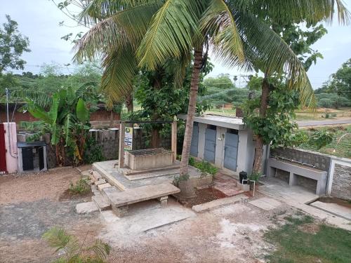 a building with a bench and a palm tree at Mithila Eco Stay - Explore chettinad in Mithilaipatti