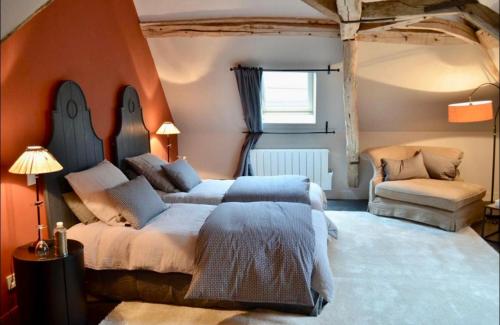 a bedroom with a large bed and a chair at Le Paddock - Chambres et table d'hôtes in Le Déluge