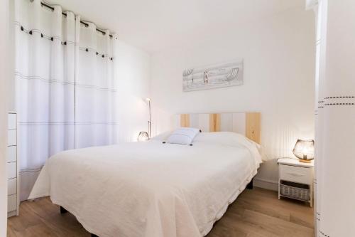 a white bedroom with a bed and a window at La Terrasse du golf in Pornic