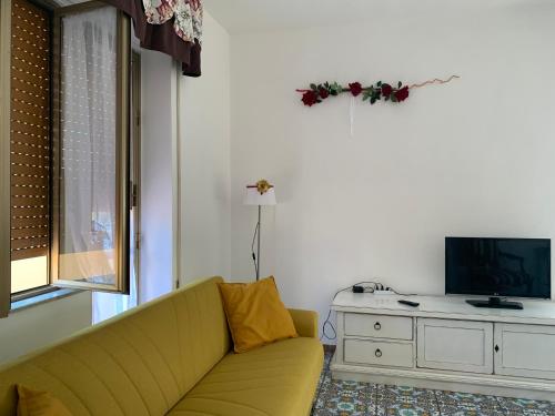 een woonkamer met een gele bank en een tv bij Sea Life House in Alghero