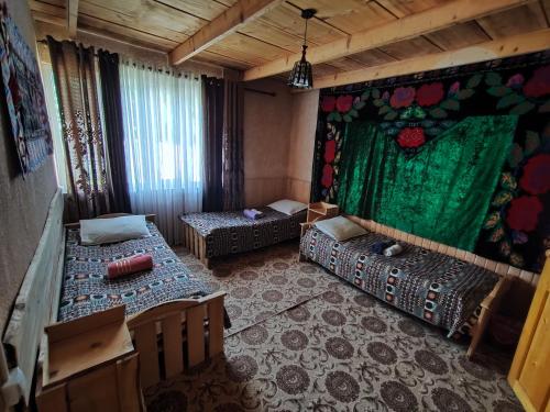 een kamer met 2 bedden en een groen gordijn bij Guest house CBT Chon-Kemin in Shabdan