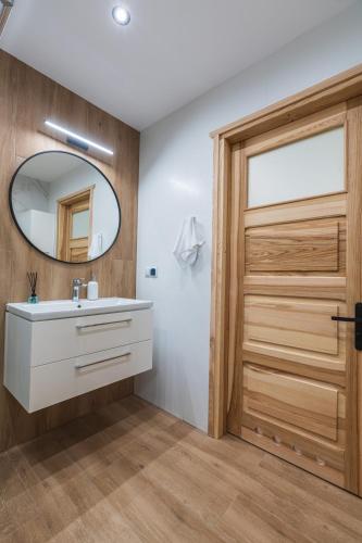 a bathroom with a white sink and a wooden door at Roztoczańska Ostoja in AdamÃ³w