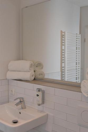 a bathroom with a sink and a mirror and towels at Landhaus Hamester - Hotel & Restaurant in Basthorst