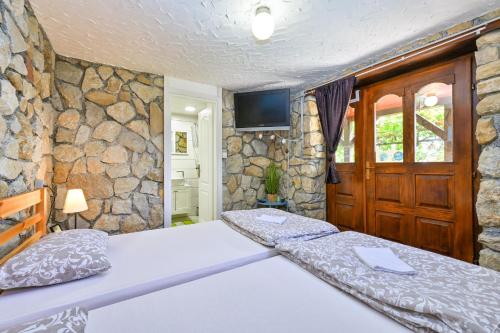 a bedroom with two beds and a stone wall at Greta Rest House in Sopot