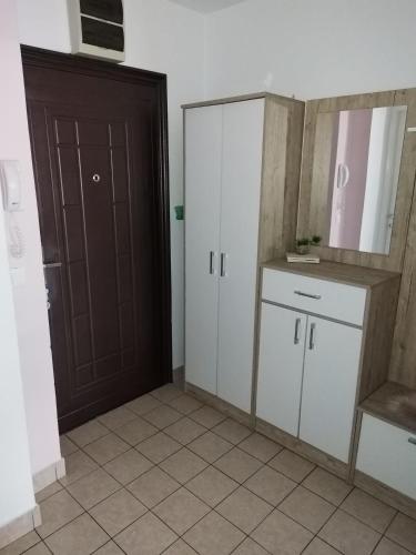 a kitchen with white cabinets and a brown door at Apartman Dea in Sarajevo