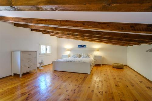 a bedroom with a white bed and a wooden floor at Eco house Zabodarski in Cunski