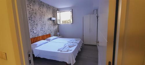 a small bedroom with two beds and a window at El Colmenar Apartamento in Madrid