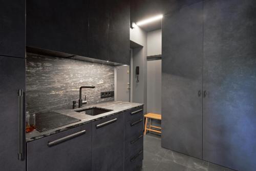 uma cozinha com armários cinzentos e um lavatório em Modern studio in bohemian Uzupis, Vilnius em Vilnius
