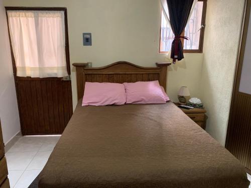 a large bed in a bedroom with a pink pillow at La Capelina Apartment in ExHacienda la Escalera in Guanajuato