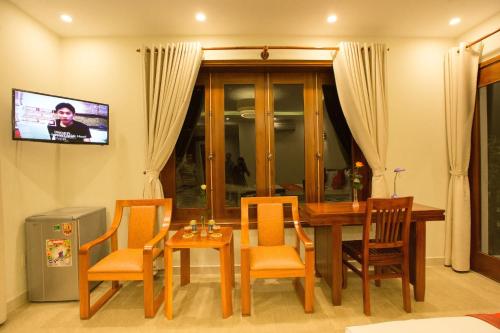 a dining room with a table and chairs and a television at Village Moon Villa in Hoi An