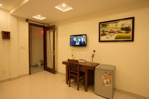 a room with a desk and a television on the wall at Village Moon Villa in Hoi An