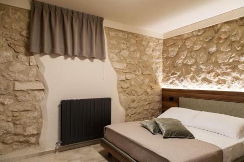 1 dormitorio con cama y pared de piedra en DESTASU' Bed and Wellness, en Castel del Monte