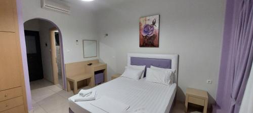 a white bedroom with a white bed and a mirror at A Vista in Parga