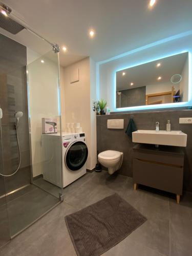 a bathroom with a shower toilet and a washing machine at MOREHOME Sonnenterrasse & Heimkino Switch 2 in Mindelheim