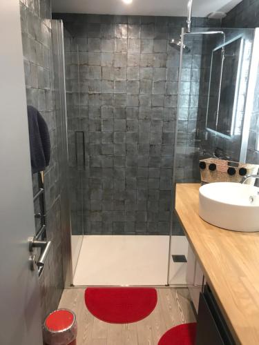 La salle de bains est pourvue d'une douche, d'un lavabo et d'un tapis rouge. dans l'établissement Appart Christelle, à La Rochelle