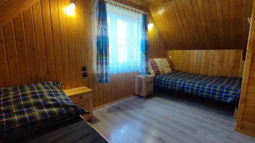 a room with two beds in a wooden room at Domki Żaklin in Polańczyk