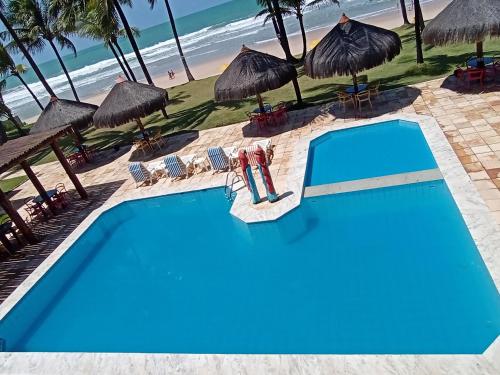 a pool with chairs and umbrellas next to the beach at Beira Mar Porto de Galinhas Hotel in Porto De Galinhas