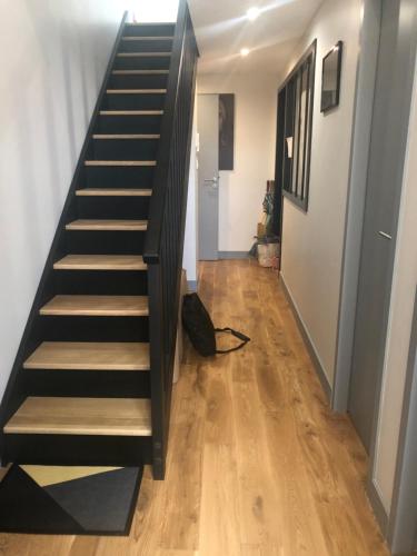 uma escada que leva até um corredor com pisos de madeira em Appart Christelle em La Rochelle