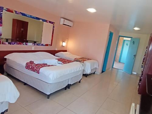a hotel room with two beds and a mirror at Beira Mar Porto de Galinhas Hotel in Porto De Galinhas