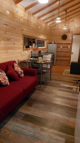 ein Wohnzimmer mit einem roten Sofa und einer Küche in der Unterkunft Cabañas El Roble in Dalcahue