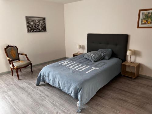 ein Schlafzimmer mit einem großen Bett und einem Stuhl in der Unterkunft F2 gatinais in Pithiviers