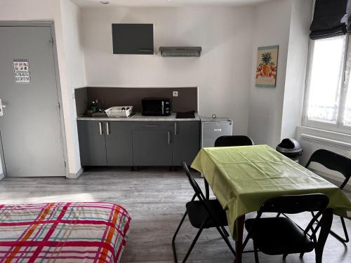 a room with a table and chairs and a kitchen at F2 gatinais in Pithiviers