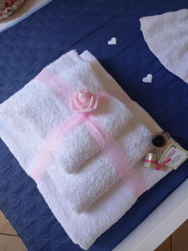 une serviette avec une rose rose sur un lit dans l'établissement Villa Serena, à Granelli