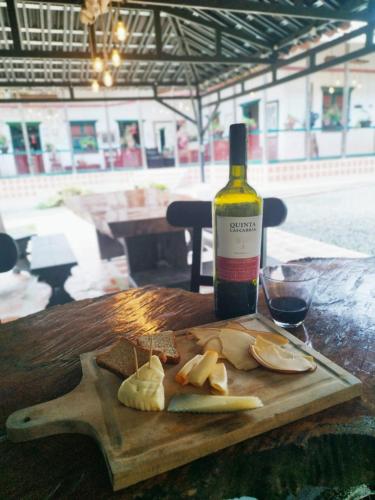 a bottle of wine and a cutting board with bread and cheese at Finca Campestre La Adelita B&B in Salento