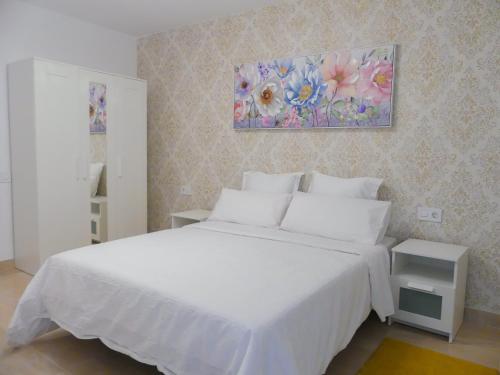 - une chambre avec un lit blanc et une peinture murale dans l'établissement Apartamentos Guadalupe Gran Canaria Puerto Rico, à Mogán