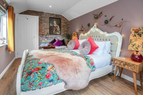a bedroom with a white bed with colorful pillows at The Loveshack Lodge Balquhidder in Balquhidder