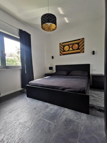 Un dormitorio con una gran cama negra y una ventana en Oasis in the city near Amfiteatar,free parking and free Wi-Fi, en Pula