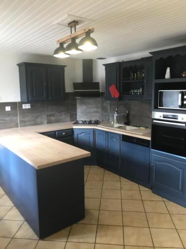 La cuisine est équipée de placards bleus et d'un four avec plaques de cuisson. dans l'établissement La Résidence de Marie, à Brommat