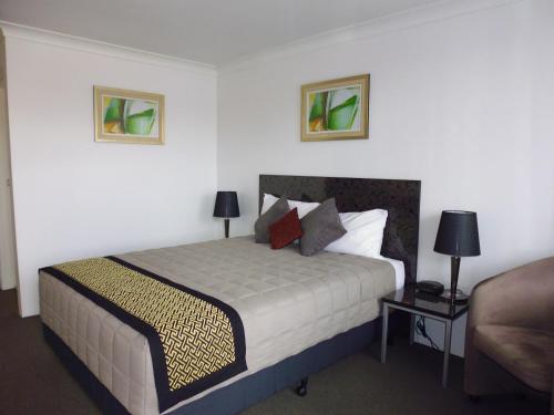 1 dormitorio con 1 cama con 2 lámparas y 1 sofá en Burke & Wills Motor Inn, en Kingaroy
