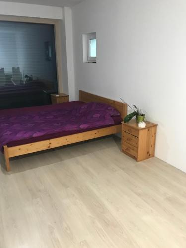 una camera con letto viola e pavimento in legno di Izba v čarovnom dome a Svätý Jur