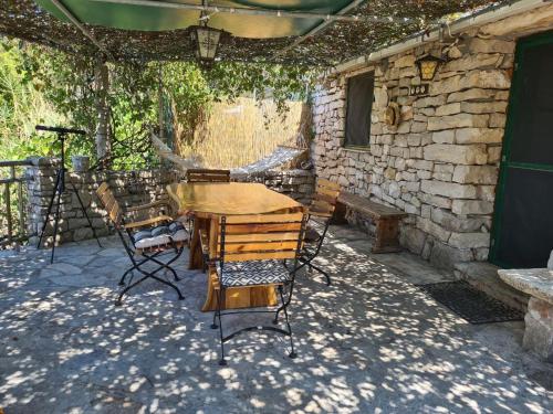 einen Holztisch und Stühle auf einer Terrasse in der Unterkunft Cottage made of stones and wood with the sea view. in Blato