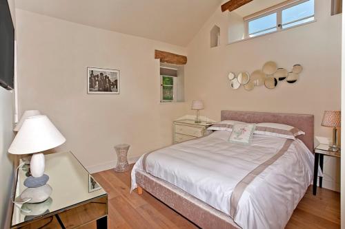 a bedroom with a bed and a table with a lamp at Valley Barn Slad Valley Cotswolds in Painswick