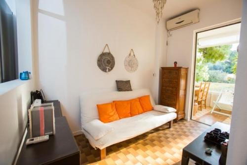 sala de estar con sofá blanco con almohadas de color naranja en Άνετη διαμονή 100 μέτρα από τη θάλασσα - Βάρκιζα, en Vari