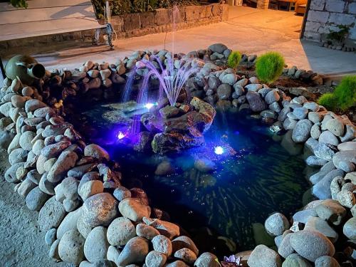 a pond with a waterfall and lights in a yard at Unoyan Guest House in Gyumri