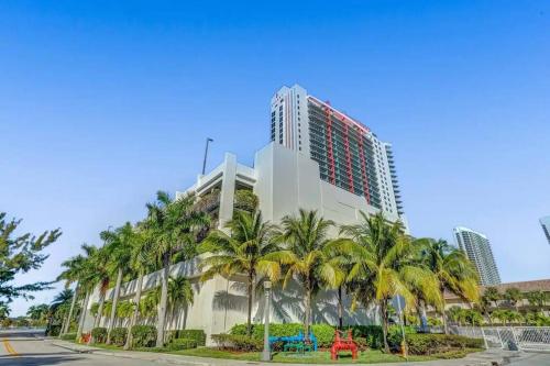 a tall building with palm trees in front of it at Lovely 2Bed 1Bath Condo With Private Balcony 18th Floor in Hallandale Beach