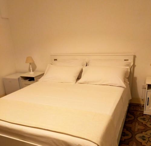 ein weißes Bett mit weißer Bettwäsche und Kissen in der Unterkunft COMES 5 HOME in Castellana Grotte