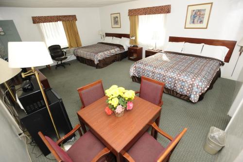 a hotel room with two beds and a table with flowers on it at Victoria Motel in Ventura