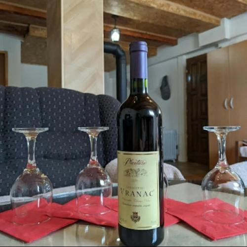 eine Flasche Wein auf einem Tisch mit zwei Weingläsern in der Unterkunft Village house Popovic in Žabljak