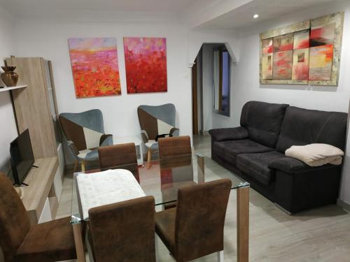 sala de estar con sofá negro y sillas en apartamento Miñes en Zaragoza