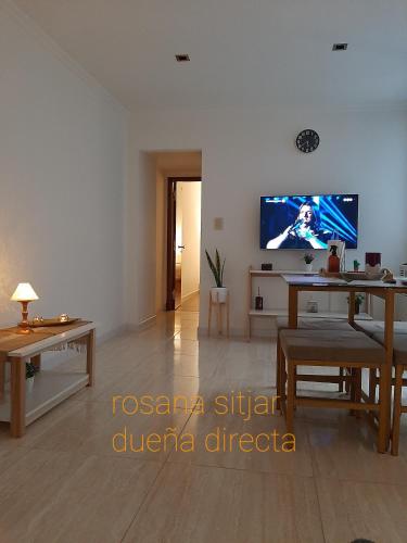 sala de estar con mesa y TV en la pared en Departamento zona plaza Colon en Mar del Plata