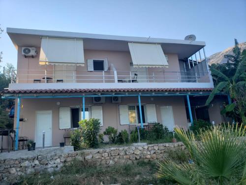 a pink house with a stone wall at Vila zaho in Dhërmi