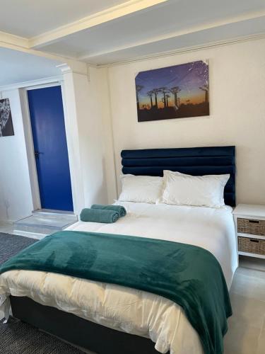 Schlafzimmer mit einem großen Bett mit blauem Kopfteil in der Unterkunft Cub's Home in Kapstadt
