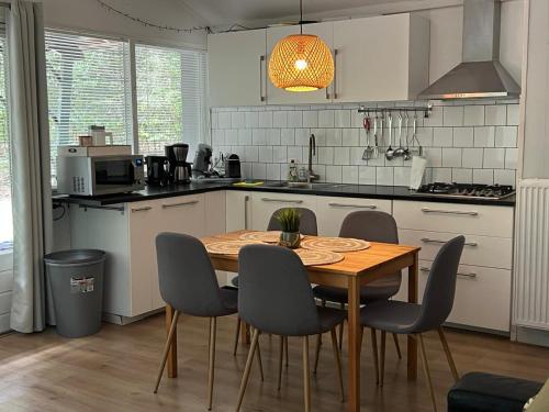Il comprend une cuisine avec une table et des chaises en bois. dans l'établissement Het Natuurhuisje op de Veluwe, à Nunspeet